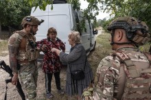 Екіпаж групи "Білих Янголів" спілкується біля броньованого автомобіля з двома жінками. Одна з них щось розповідає. Дія на вулиці.