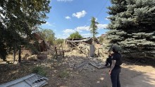 Правоохоронець стоїть біля зруйнованого окупантами одноповерхового будинку