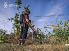 Піротехнік ДСНС розміновує території від небезпечних залишків війни. Чоловік стоїть з металошукачем у повній екіпіровці.