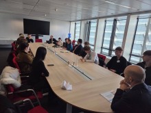 Делегація на робочої зустрічі сидить за столом.