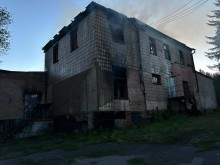 Двоповерхова будівля, яка горить зсередини через обстріл.