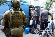Поліцейський чатує на воожі дрони, поки люди сідають в авто для евакуації