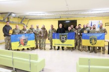 Вадим Філашкін разом з бійцями тримають прапори підрозділів та нагороди
