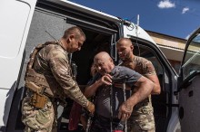 Екіпаж "Білих янголів" евакуював з міста Білицьке, маломобільних  людей. Чоловік похилого віку якого тримають поліцейські під руки перед посадкою до броньованого автомобіля.