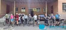 Велотуристи перед початком заїзду. Чоловіки,жінки та діти тримають велосипеди за руль та посміхаються.