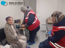 Фахівці Червоного Хреста міряють тиск жінці похилого віку