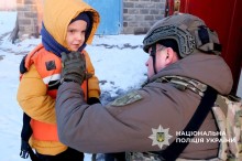 Поліцеський вдягає хлопчику дитячий бронежилет