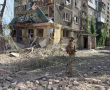 Правоохоронець стоїть біля зруйнованої багатоповерхівки
