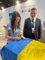 Представники Бахмутської громади на конференції з відновлення України у Римі підписують прапор.