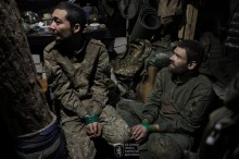 Двоє чоловіків у формі загарбника, сидять зі зв'язаними руками.