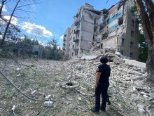 Правоохоронець стоїть біля зруйнованої окупантами багатоповерхівки.