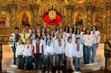 Групове фото дитячого хору у вишиванках біля позолоченого іконостаса в церкві