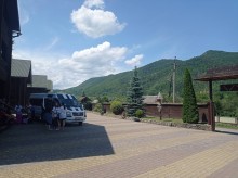 Гостинний двір. З обох сторін гори. На дворі стоїть мікроавтобус, поруч дівчата.