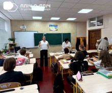 Шкільний клас. Біля дошки стоїть вчитель проводить заняття, діти сидять за партами.