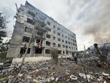 Зруйнована ворожим обстрілом багатоповерхівка з вибитими вікнами та пошкодженим фасадом.