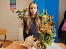 Дівчина, вихованка Донецького обласного центру технічної творчості дітей та юнацтва, біля рослинної композиції