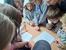 Група дітей займається складанням шифрів для квесту. На білих аркушах паперу вони малюють символи.