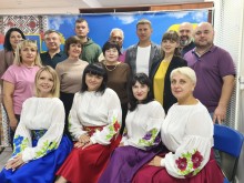 Спільне фото представників громад. Жінки на першому ряду, одягнені у вишиванки та кольорові спідниці.