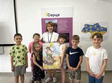 Група дітей та вихователька тримають патріотичний плакат «З Днем Конституції!» на тлі карти України та постера з написом «Я - серце».