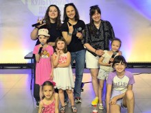 Жінки з дітьми тримають мікрофони та посміхаються