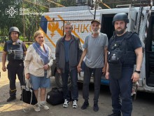 Троє мешканців Дружківки стоять з рятувальниками біля евакуаційного автомобіля