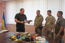 Очільник Дружківської громади Андрій Панков розповідає про книгу захисникам. Військові уважно слухають.