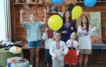 Діти та дорослі у вишиванках позують в кімнаті, прикрашеній синіми та жовтими кульками