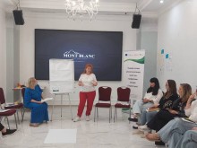 Тренерка розповідає та пише на дошці для працівниць соціальної сфери, як ефективно реагувати на випадки гендерно зумовленого насильства у періоди кризових ситуацій.