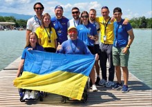 Спортсмени на пірсі тримають в руках державний прапор.