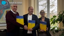Представники громад. З теками жовто-блакитного кольору. Посміхаються та тиснуть один одному руки.