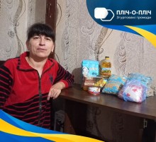 Жінка сидить біля столу з гуманітарною допомогою