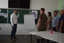 Міський голова Михайло Світлик та начальник Очеретинської селищної військової адміністрації Микола Коваленко разом з представниками громад стоять у класі та обговорюють питання про співпрацю.