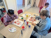 Дві жінки зблизька розфарбовують квіткові та геометричні візерунки червоними та зеленими фарбами