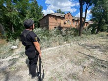 Правоохоронець стоїть поруч з пошкодженим будинком.