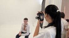 Фотографиня знімає хлопця у білій вишиванці, який сидить на стільці у фотостудії