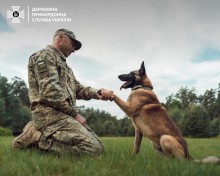 Український прикордонник вітається зі службовою собакою, який дає лапу