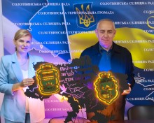 Начальник Мангушської селищної військової адміністрації наталя Воробйова передає голові Солотвинської громади символічну карту