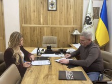 Підписання Меморандуму про співробітництво між Новогродівською та Тячівською громадами. Заступники голів громад сидять за столом та підписують документ