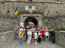 Спільне фото дітей. Діти стоять біля входу до замку, зверху прапори України.