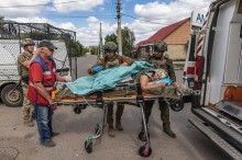 Парамедики поліції везуть каталку з літньою жінкою, яку треба завантажити до спецавтомобіля