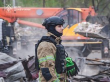 Спеціалізована будівельна техніка, яка допомагає розбирати руйнування, поруч стоїть рятувальник.