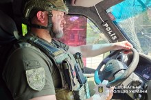 Поліцейський за кермом евакуаційного автомобіля. Зосереджений на дорозі.