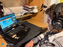 Учень сидить біля екрану монітора у навушниках.