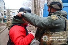 Полійейський вдягає на хлопчика каску та бронежилет