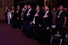 Учасники форуму співають гімн України та тримають руки біля серця.
