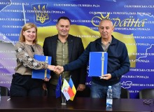 Начальник Мангушської селищної військової адміністрації Наталія Воробйова та голова Солотвинської селищної територіальної громади Василь Йовдій, тиснуть один одному руки після підписання меморандуму.