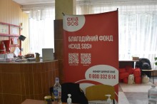 Банер з назвою благодійної організації на червоному фоні білими буквами написано "Схід SOS".