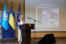 Заступниця Новогродівського міського голови Ольга Сидорова. Стоїть на сцені, позаду неї прапори: ООН, України та Євросоюзу. З боку на екрані демонстрація цифрових рішень, впроваджені на Донеччині в умовах війни.