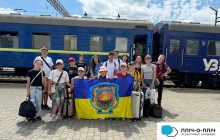 Діти Званівської громади біля потяга на пероні залізничного вокзалу, тримають прапор громади.