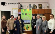 Освітяни стоять у класі, фото з банером з надписом "Освітній хаб Торецької громади".
